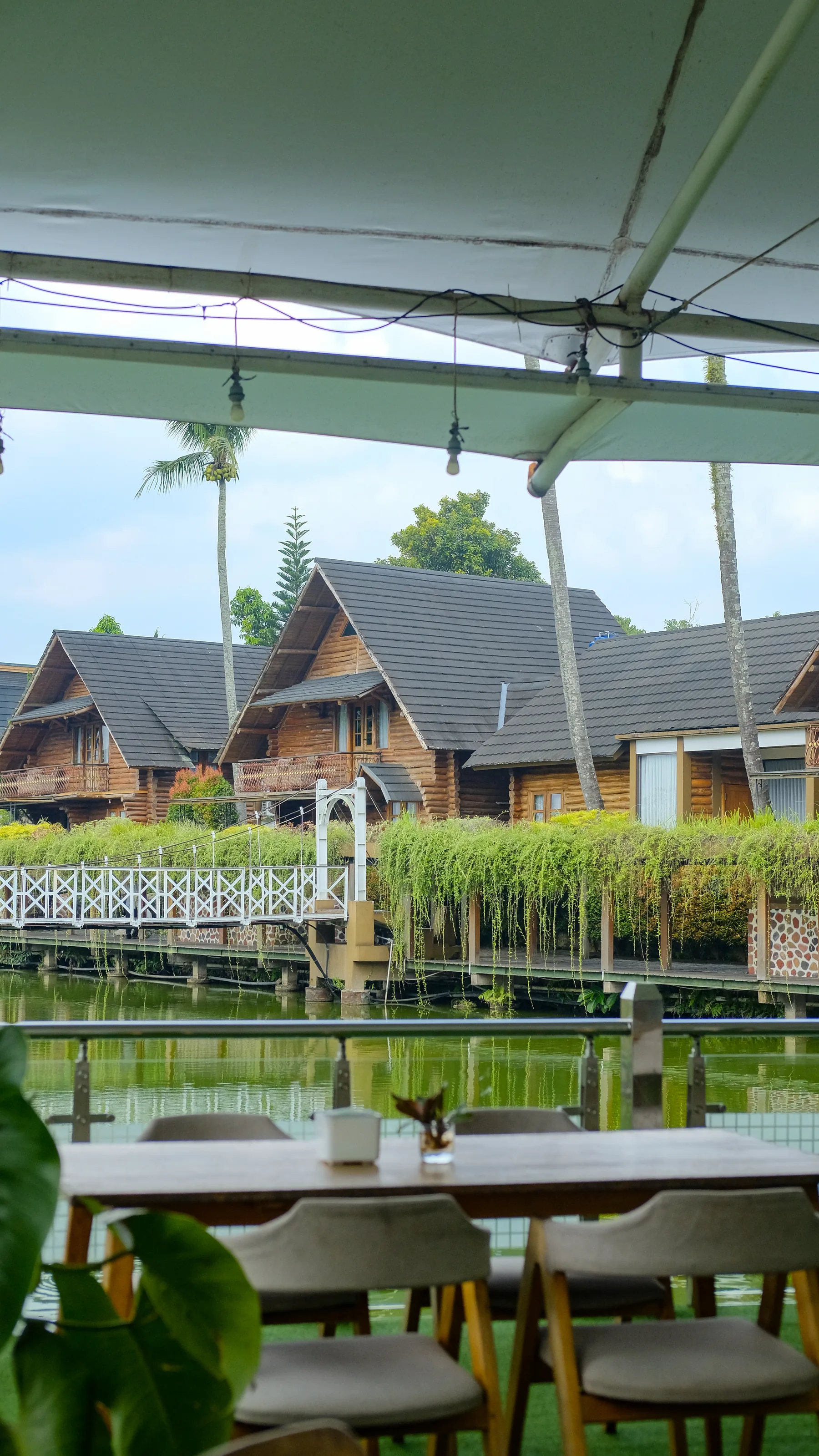 Meja makan Arummanis Restaurant menghadap danau dan cottage kayu